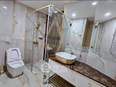 Luxurious marble bathroom with elegant fixtures and glass shower enclosure.