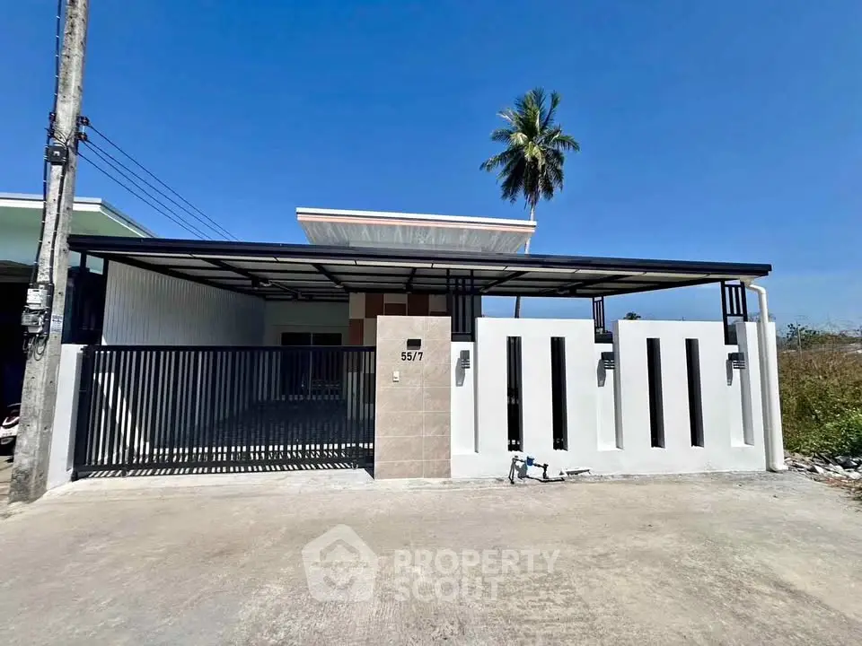 Modern single-story house with sleek gate and palm tree backdrop