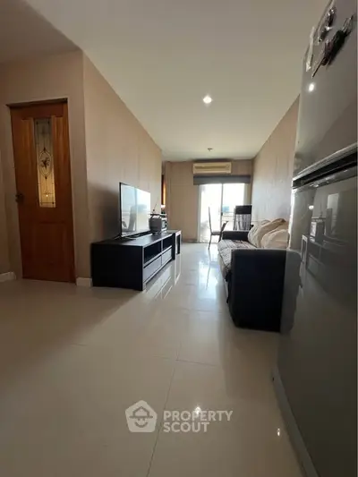 Spacious living room with modern decor and natural light, featuring a sleek TV unit and comfortable seating.
