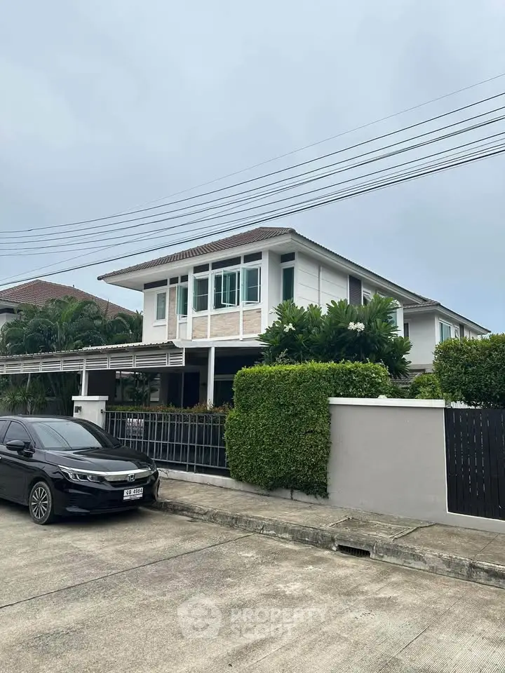 Modern two-story house with lush greenery and sleek car parked in driveway, perfect suburban living.