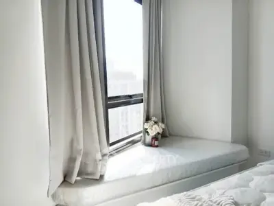 Bright bedroom with cozy window seat and city view, perfect for relaxation.