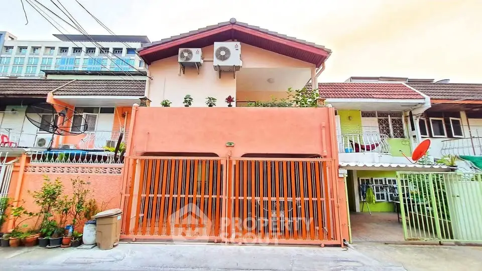Charming two-story townhouse with vibrant facade and gated entrance in urban neighborhood.