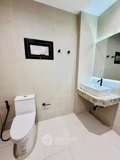 Modern bathroom with sleek fixtures and elegant tile design, featuring a contemporary sink and toilet.