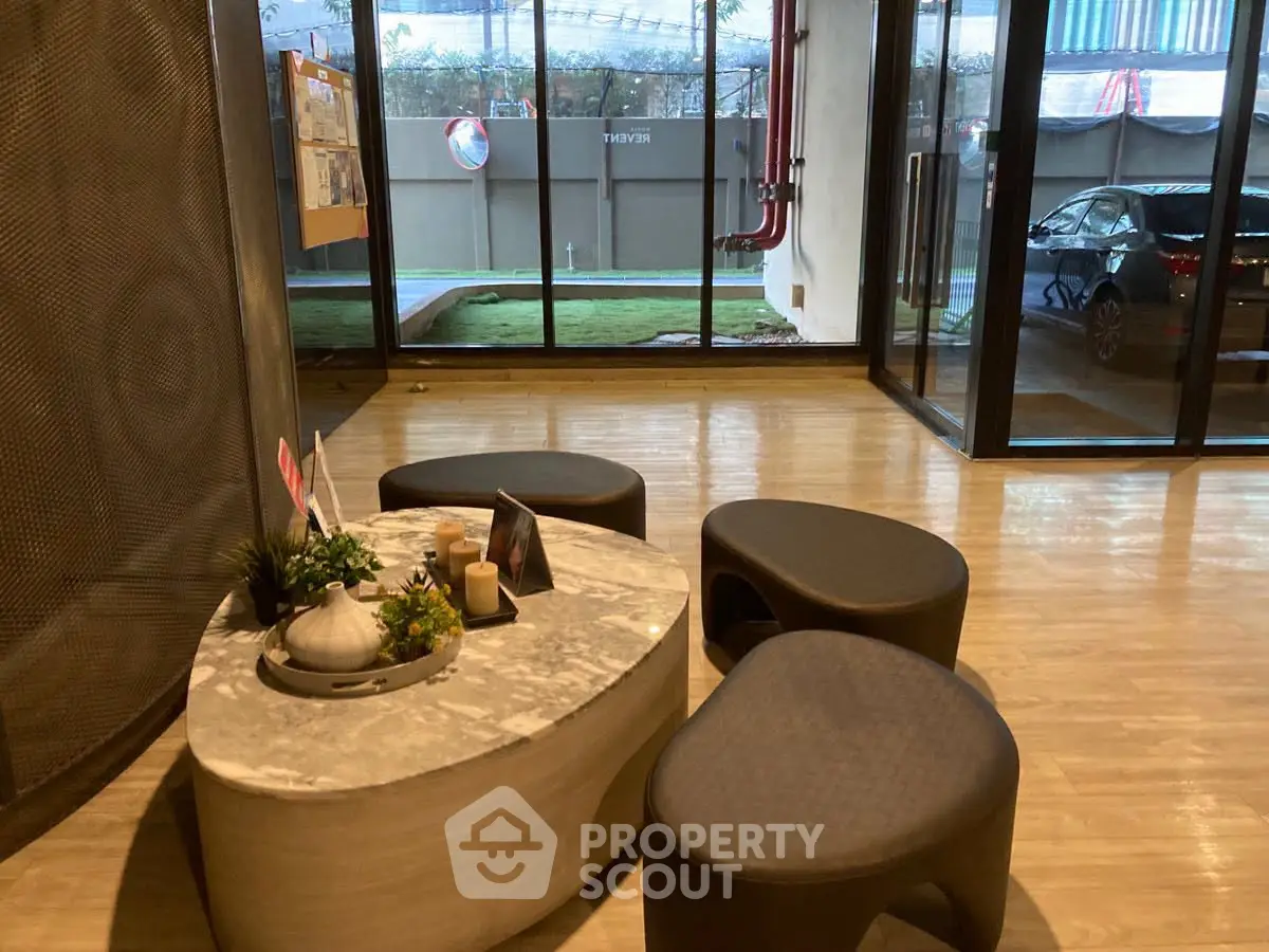 Modern building lobby with stylish seating and glass doors leading to outdoor area.