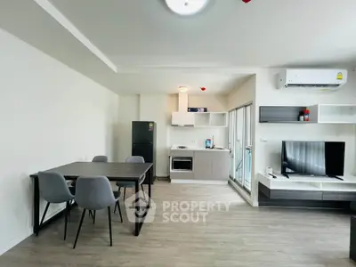 Modern open-plan living room with dining area and sleek kitchen appliances.