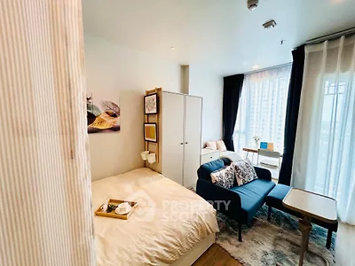 Modern studio apartment with cozy living area and large windows offering city views.