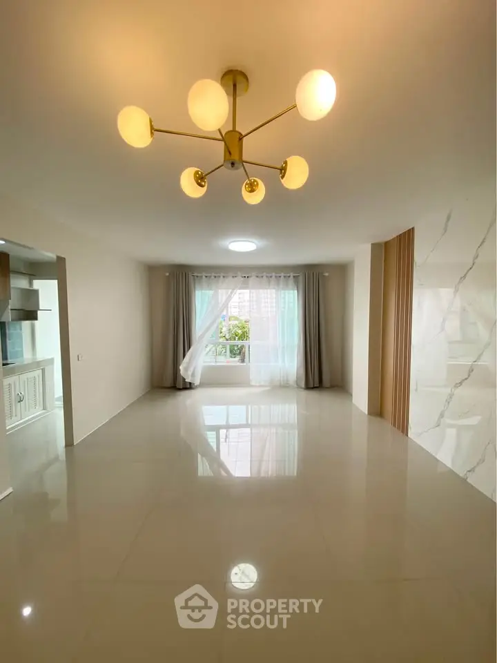 Spacious modern living room with elegant chandelier and large windows for natural light.