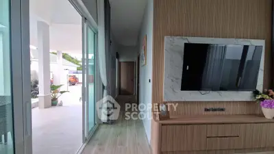 Modern living room with sliding glass doors and wall-mounted TV, opening to a spacious patio.