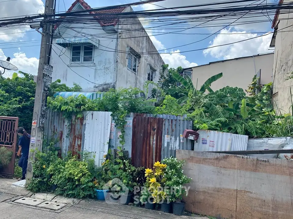 Charming fixer-upper house with lush garden in urban setting, perfect for renovation enthusiasts.