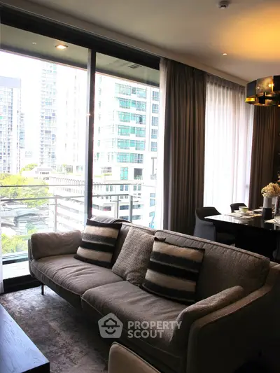 Modern living room with large windows and city view, featuring stylish furniture and elegant decor.