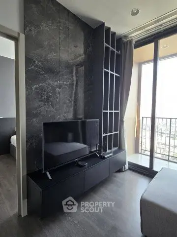 Modern living room with sleek black TV stand and floor-to-ceiling windows leading to a balcony.