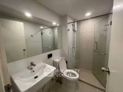 Modern bathroom with glass shower and sleek fixtures in contemporary apartment.