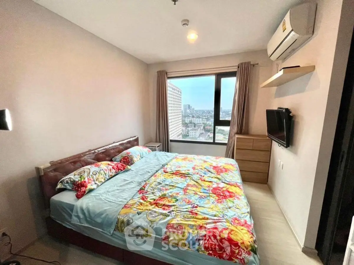 Modern bedroom with city view, featuring a cozy double bed and wall-mounted TV.