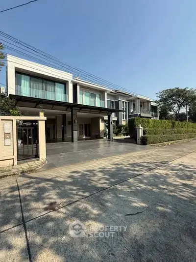 Modern two-story house with large windows and driveway in a serene neighborhood.
