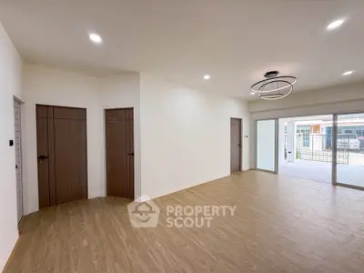 Spacious modern living room with wooden flooring and large windows for natural light.