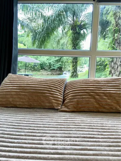 Luxurious bedroom with plush bedding and scenic forest view through large windows.