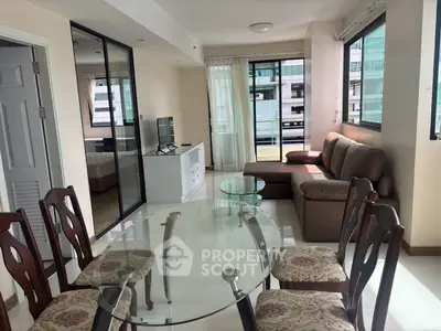 Spacious living and dining area with modern furniture and large windows in a city apartment.