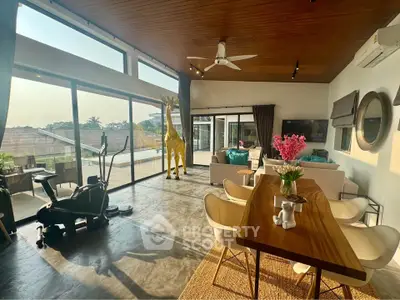 Spacious modern living room with large windows and stylish decor, featuring a unique giraffe sculpture.