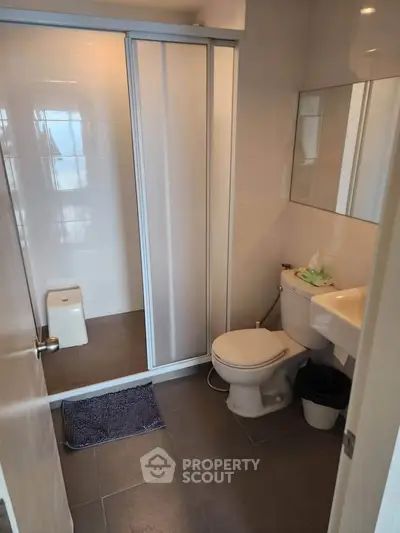 Modern bathroom with shower, toilet, and sink in a sleek real estate property.