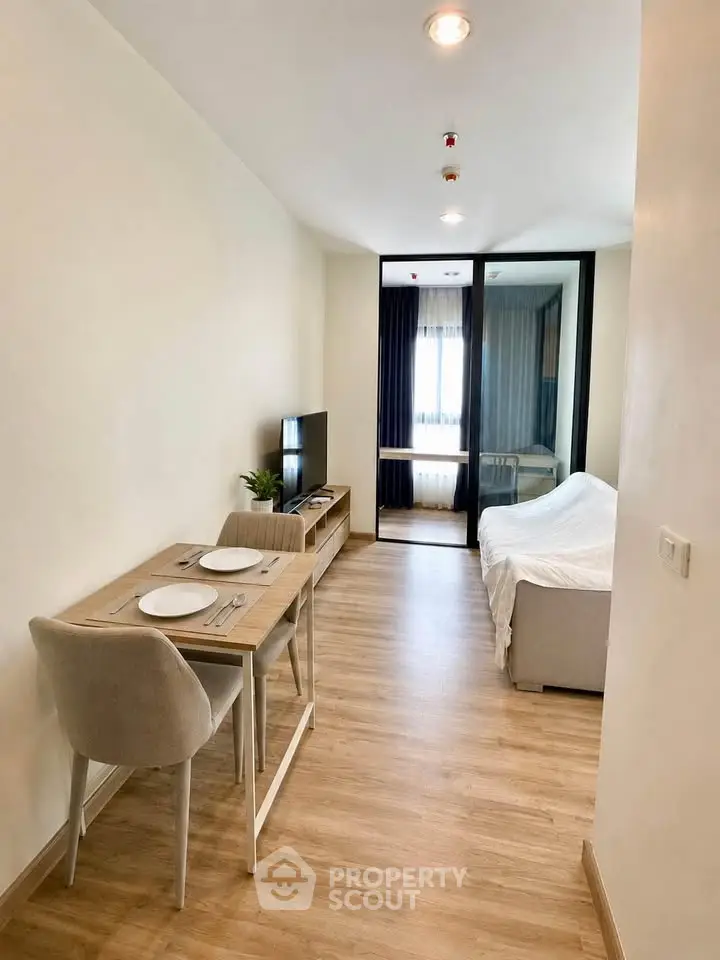 Modern studio apartment with cozy living area and dining space, featuring sleek wooden flooring and natural light.