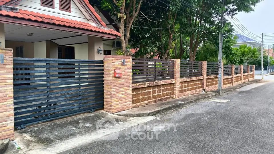 Charming suburban house with brick fence and lush greenery, perfect for family living.