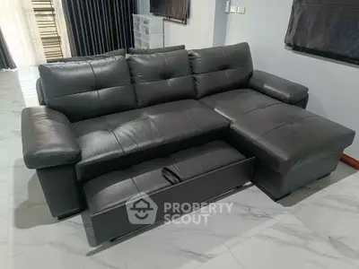 Luxurious black leather sectional sofa in modern living room with marble flooring and elegant curtains.