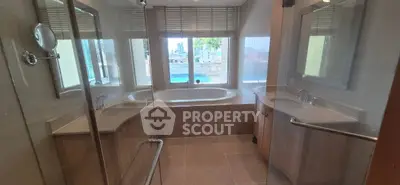 Luxurious bathroom with dual sinks and a large bathtub offering city views.