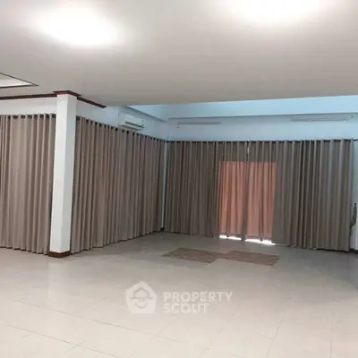 Spacious living room with large windows and elegant curtains, perfect for natural light and modern living.