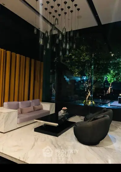 Luxurious living room with high ceiling, unique pendant lights, marble flooring, and stylish furniture overlooking a serene outdoor garden.