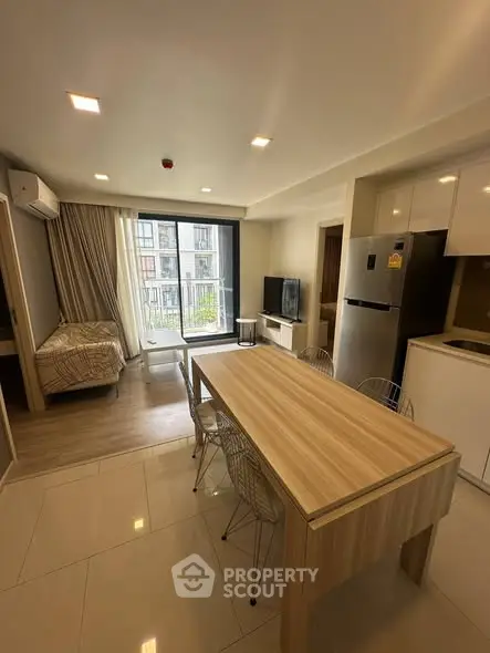 Modern studio apartment with open layout, featuring a cozy living area, dining table, and kitchenette.