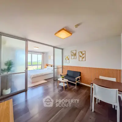 Modern apartment interior with sliding doors, cozy living area, and bright bedroom view.