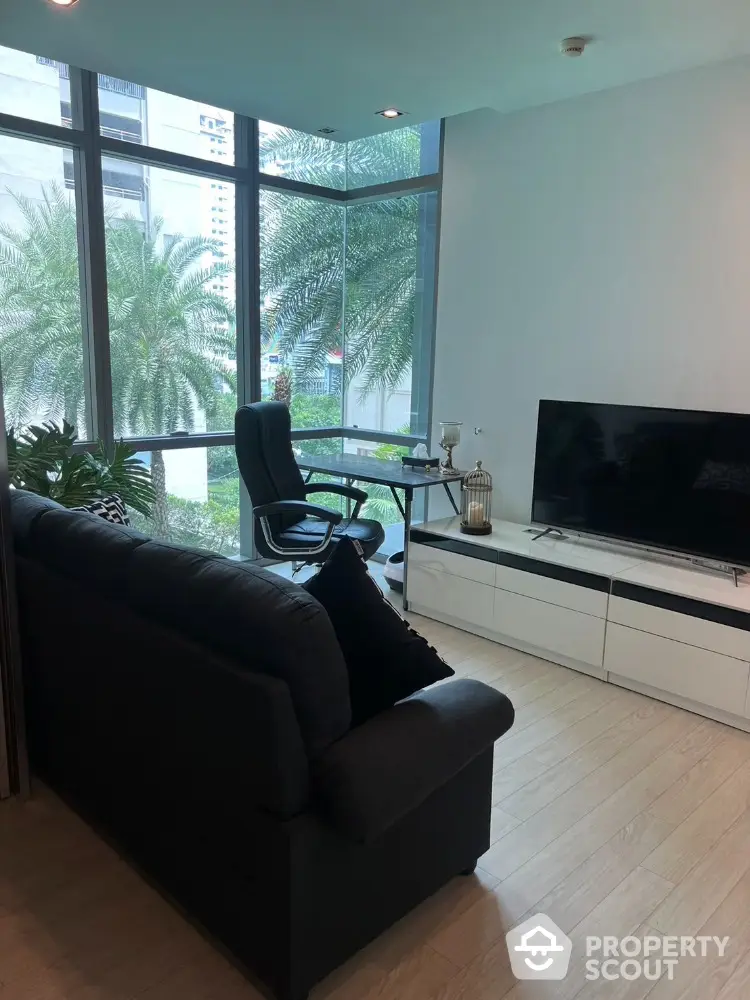 Modern living room with large windows and city view, featuring sleek furniture and natural light.