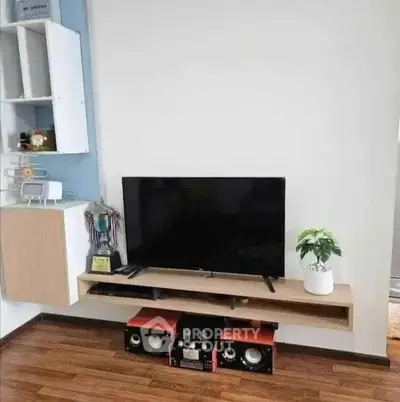 Modern living room with sleek TV setup and stylish wooden flooring.