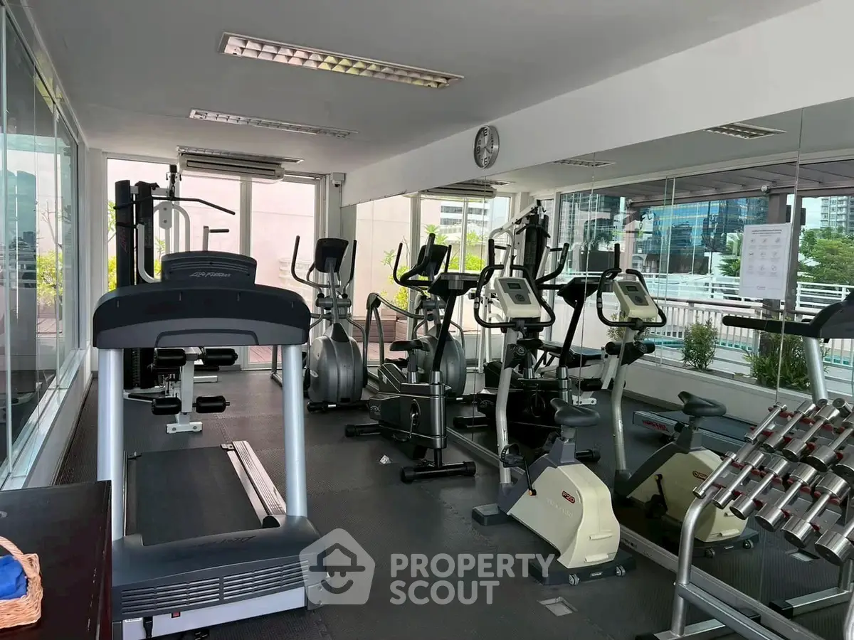 Modern gym with cardio equipment and city view, perfect for fitness enthusiasts.