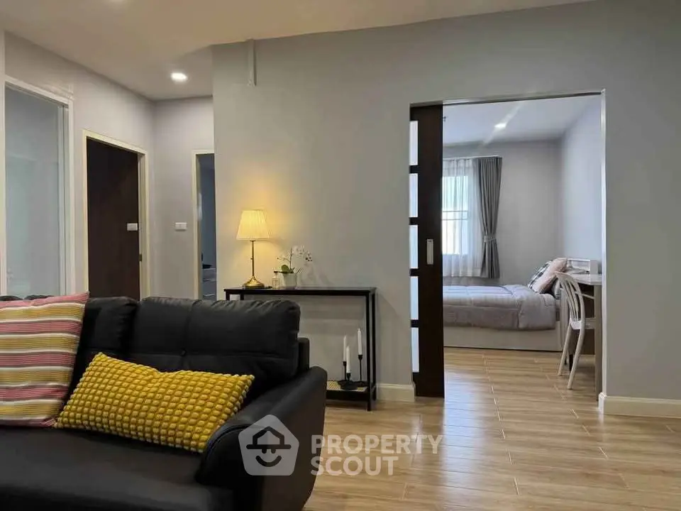 Modern living room with cozy seating and view into a stylish bedroom, perfect for comfortable living.
