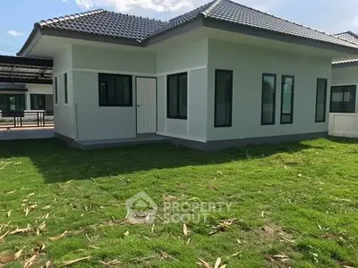 Modern single-story house with large windows and green lawn, perfect for family living.