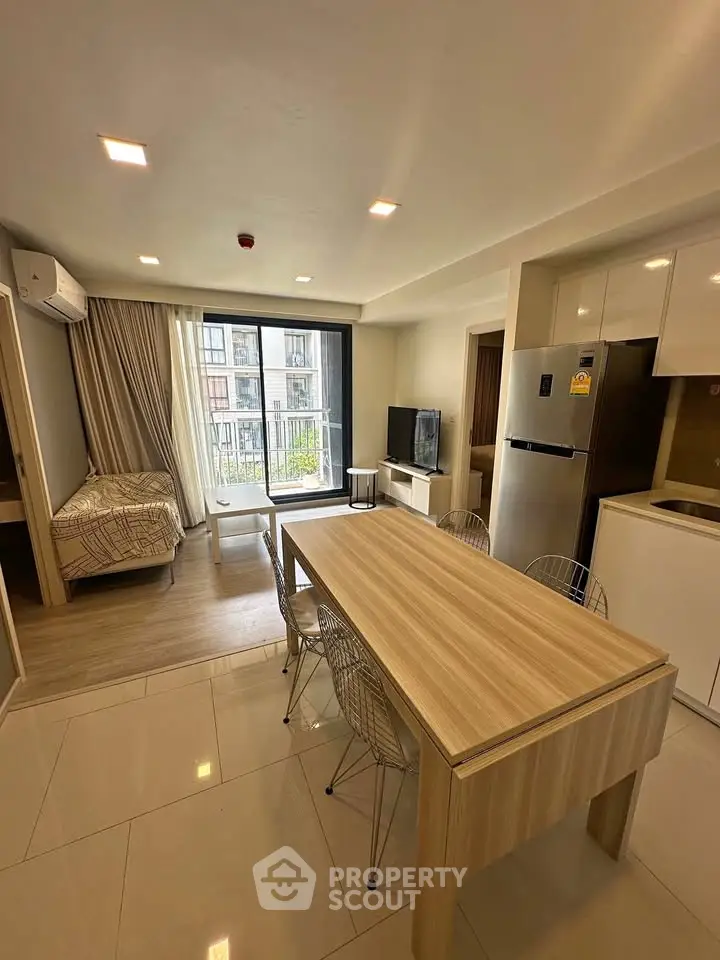 Modern studio apartment with open layout, featuring a cozy living area, dining table, and kitchenette.