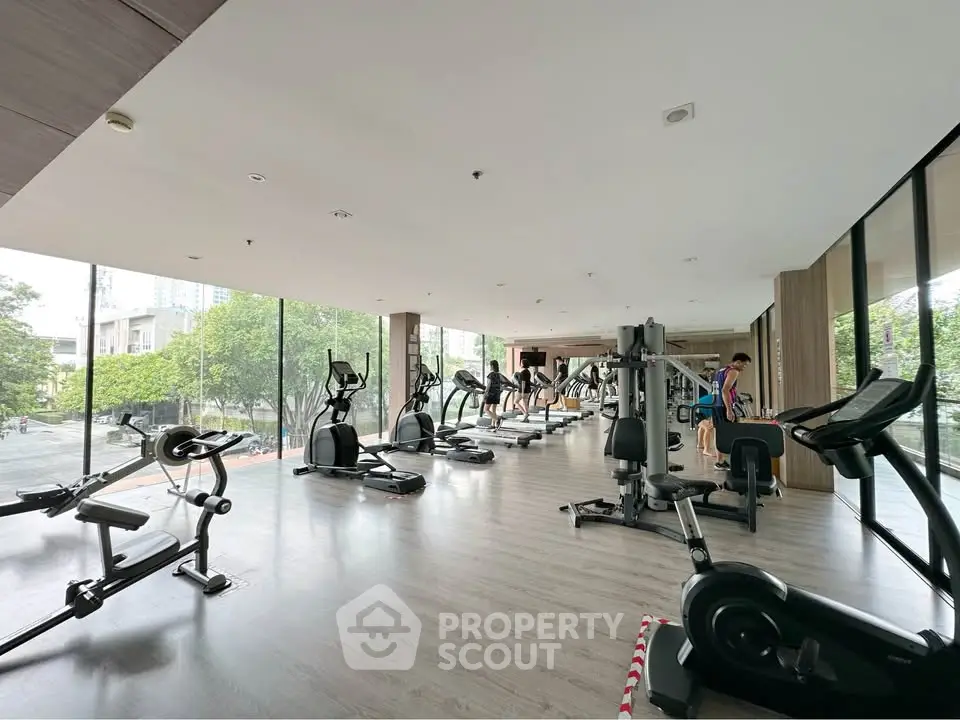 Spacious modern gym with large windows and state-of-the-art equipment in a luxury building.
