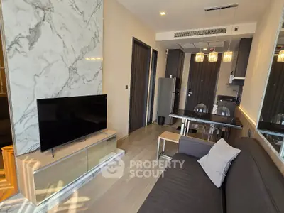 Modern living room with sleek design, marble accent wall, and open kitchen layout in a stylish apartment.