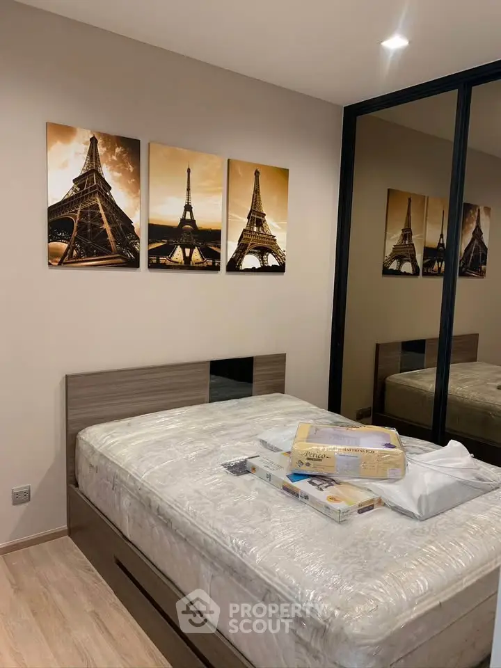 Modern bedroom with mirrored wardrobe and stylish Eiffel Tower artwork.