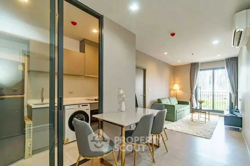 Modern open-plan living room with kitchen and dining area, featuring stylish furniture and natural light.