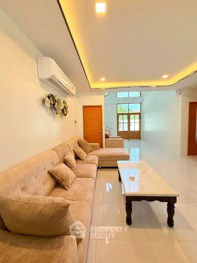 Spacious living room with plush seating and modern decor, featuring a sleek air conditioning unit and elegant lighting.