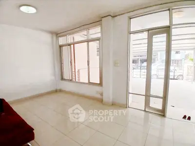 Spacious living room with large windows and tiled flooring