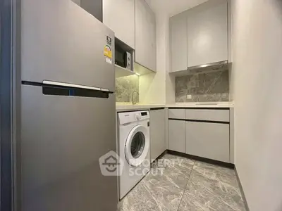 Modern kitchen with washing machine and sleek cabinetry in compact space.