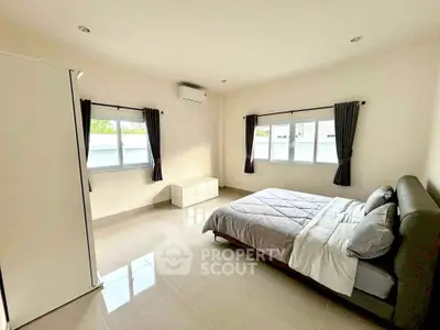 Spacious and bright bedroom with modern furnishings and large windows.