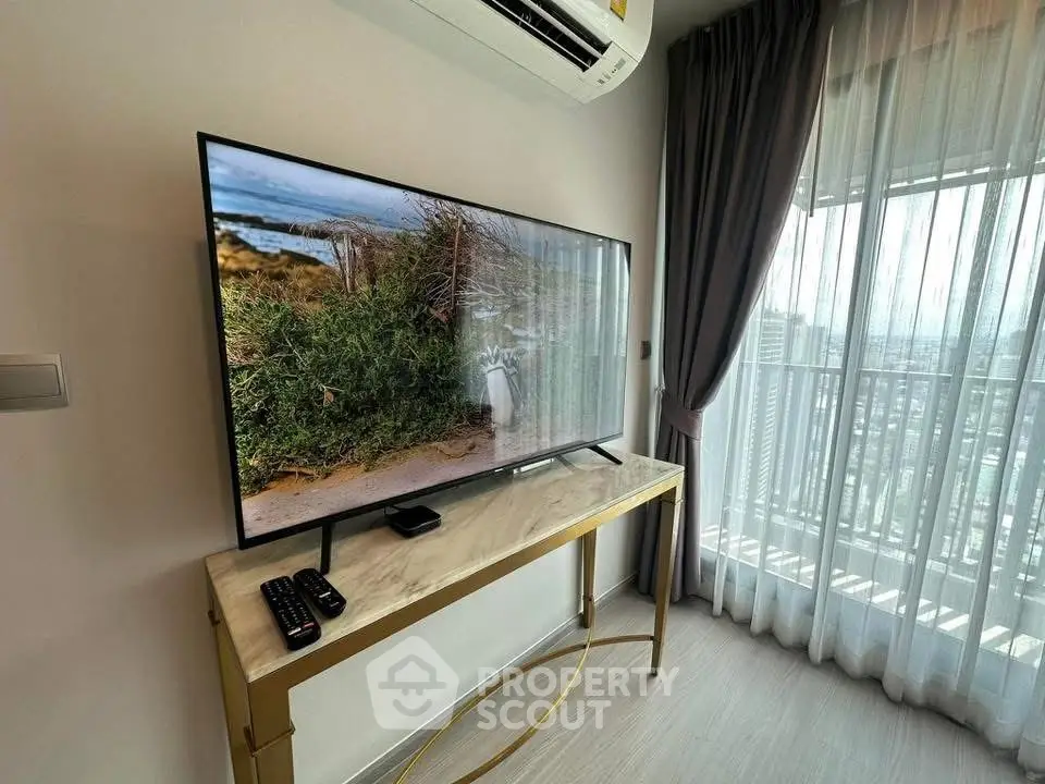 Modern living room with TV and balcony view in high-rise apartment