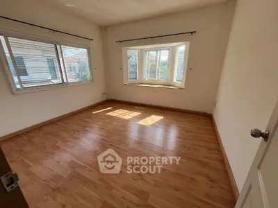 Spacious empty room with large windows and wooden flooring, ideal for customization.