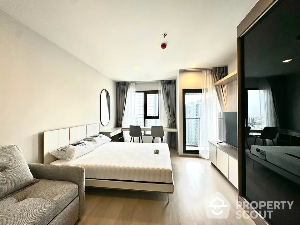 Modern bedroom with city view, stylish furnishings, and ample natural light