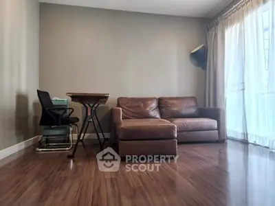Spacious living room with leather sofa and wooden flooring, perfect for modern living.