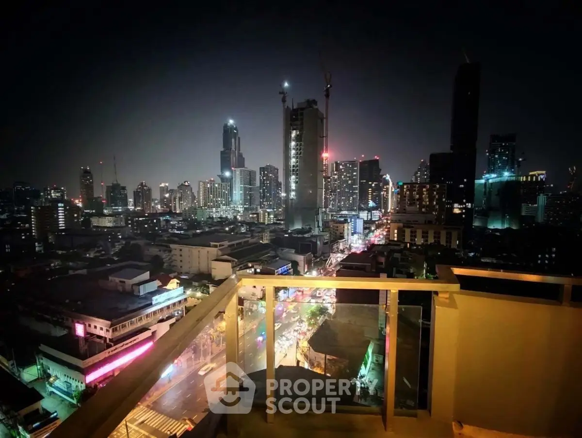 Stunning city skyline view from a high-rise balcony at night, showcasing vibrant urban lights.